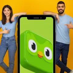 Para, co po 5 poziomie Duolingo? Młodzi ludzie wskazują na ekran telefonu z sową Duo.