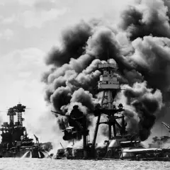 Okręty płoną po ataku, który był jedną z przyczyn ataku na Pearl Harbor. Dym zasnuwa niebo nad zatoką.