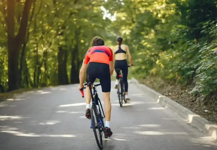 Dwie osoby na rowerach jadące leśną drogą. Można by pomyśleć, jak obliczyć średnią prędkość tej przejażdżki.