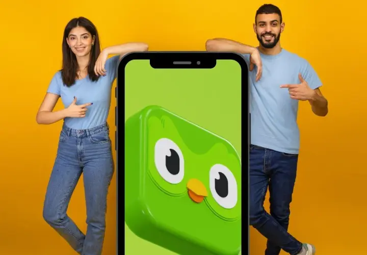 Para, co po 5 poziomie Duolingo? Młodzi ludzie wskazują na ekran telefonu z sową Duo.