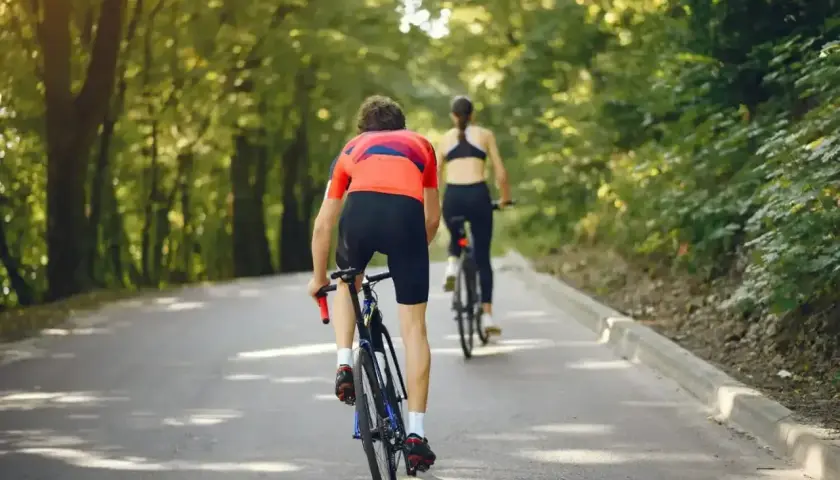 Dwie osoby na rowerach jadące leśną drogą. Można by pomyśleć, jak obliczyć średnią prędkość tej przejażdżki.