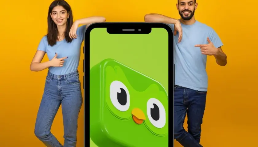 Para, co po 5 poziomie Duolingo? Młodzi ludzie wskazują na ekran telefonu z sową Duo.