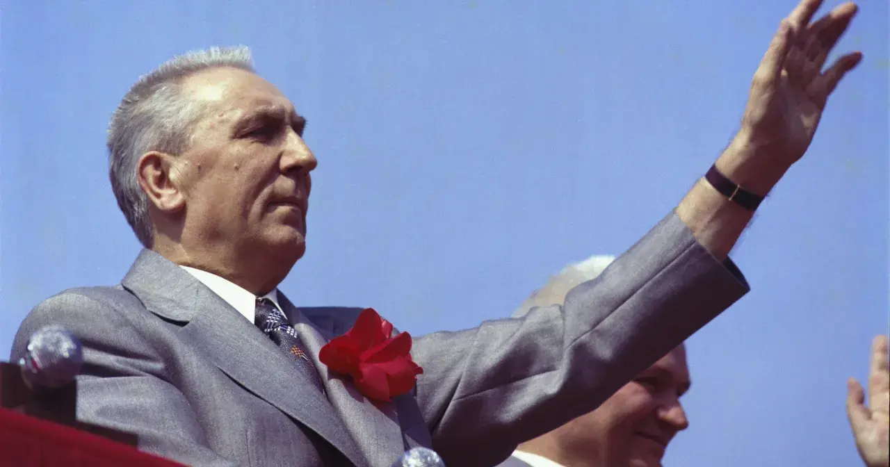 Edward Gierek, wznosząc rękę, symbolizuje czasy, gdy starał się budować Polskę, inwestując w rozwój przemysłu i poprawę bytu obywateli.