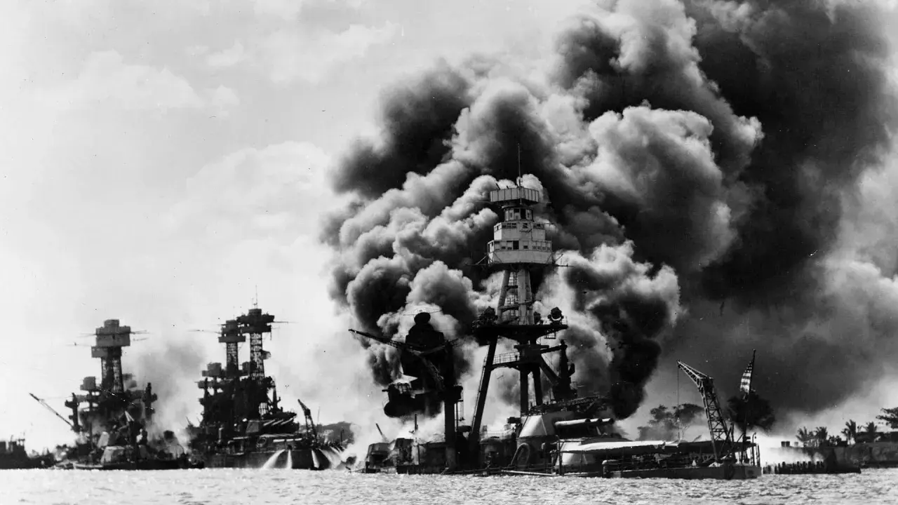 Okręty płoną po ataku, który był jedną z przyczyn ataku na Pearl Harbor. Dym zasnuwa niebo nad zatoką.
